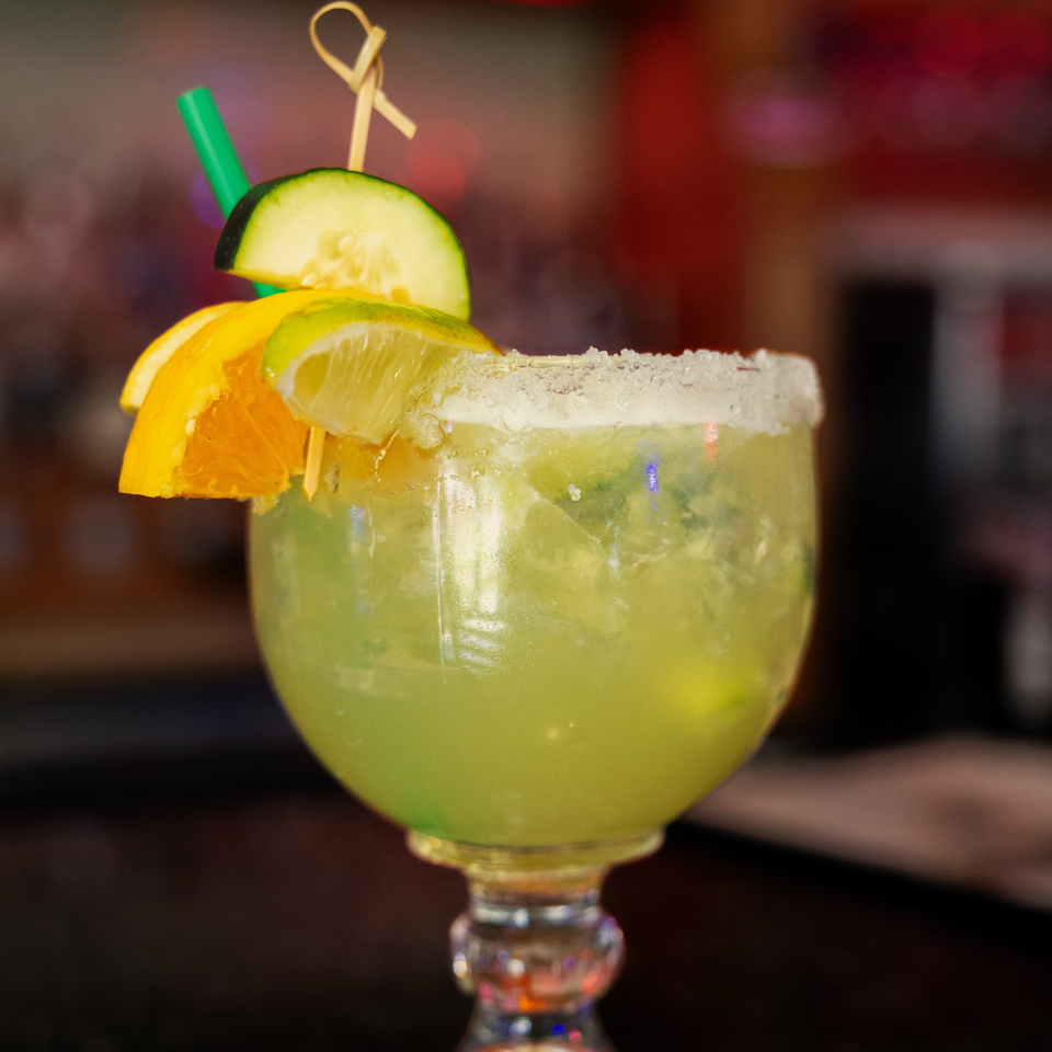A La Casa del Sol margarita garnished with orange, lime, and cucumber slices, and a salted rim.
