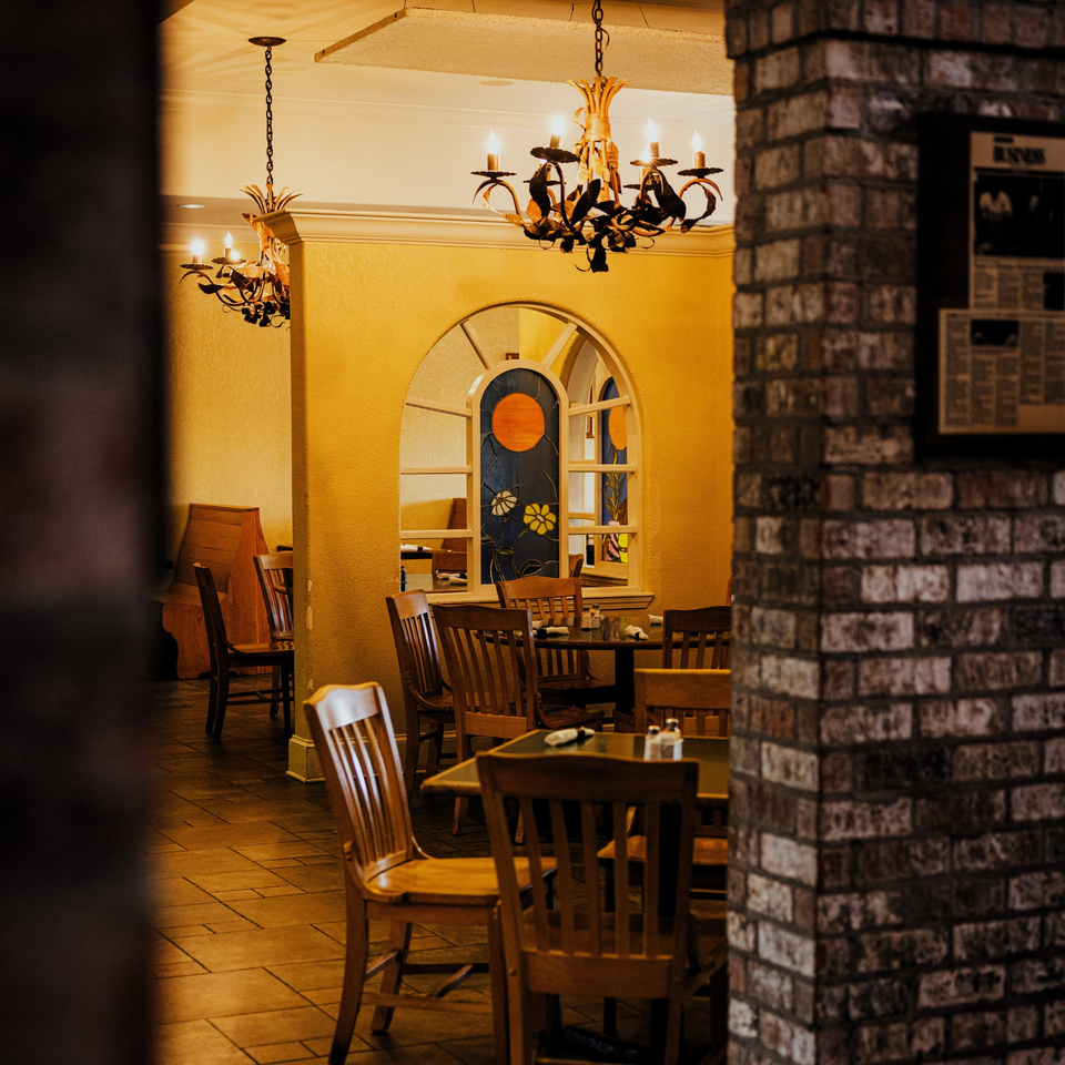 Warmly lit interior of La Casa del Sol, featuring wooden tables, chairs, and stained-glass windows.